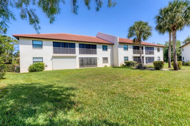 507 Pine Hollow Cir Unit 507, Englewood, FL 34223 - rear view of property with stucco siding, a lawn, a tile roof, and a garage