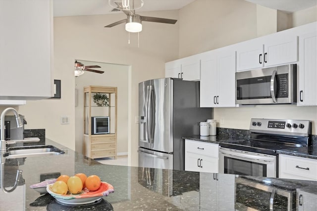 kitchen with stainless steel appliances, a ceiling fan, a sink, white cabinets, and a high ceiling