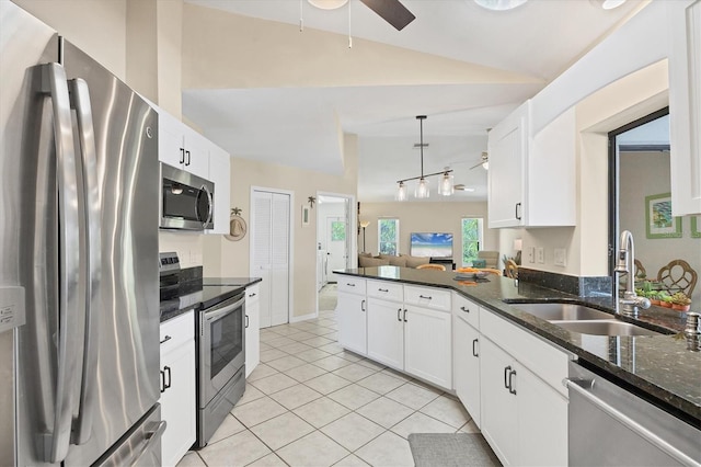 kitchen with appliances with stainless steel finishes, a sink, lofted ceiling, light tile patterned flooring, and white cabinetry
