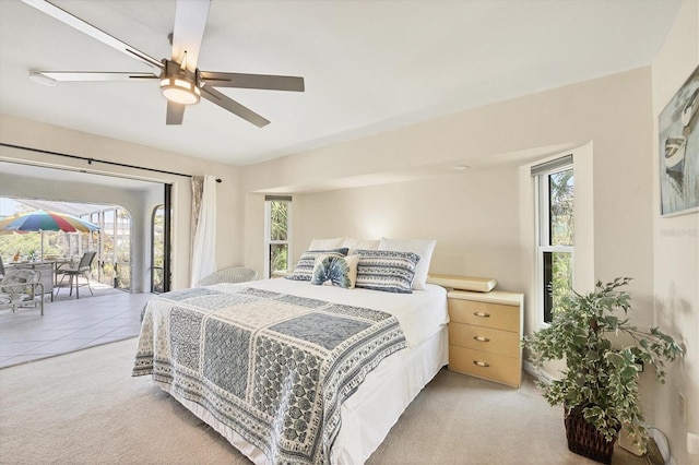 bedroom with access to outside, light colored carpet, and a ceiling fan