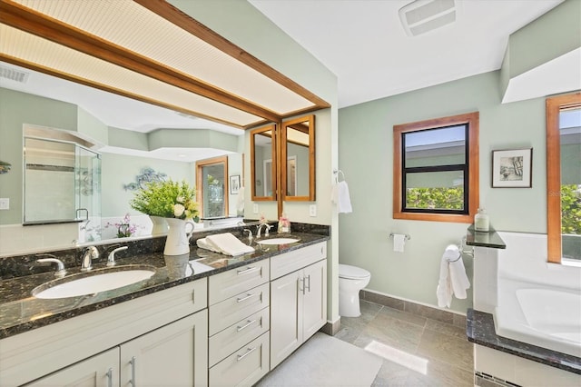 full bath featuring a stall shower, stone tile flooring, baseboards, toilet, and double vanity
