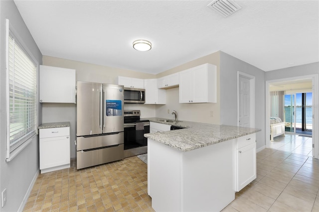 5041 N Beach Road 2A And 2B, Englewood, FL 34223 - kitchen with stainless steel appliances, baseboards, a sink, a peninsula, and light stone counters