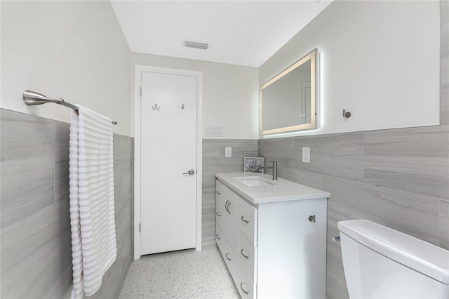 1691 Lakeview Pl, Englewood, FL 34223 - bathroom with tile walls, vanity, toilet, wainscoting, and speckle patterned floor