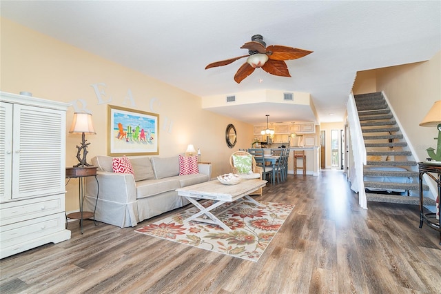 living room with wood finished floors, ceiling fan, and stairs