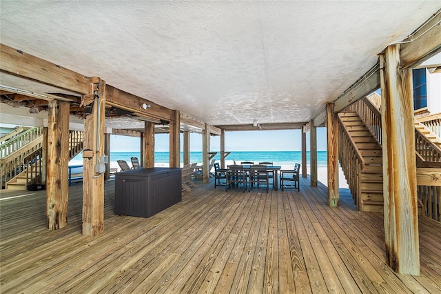 deck with stairway, a water view, and outdoor dining area
