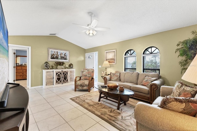 living area with a ceiling fan, vaulted ceiling, light tile patterned flooring, and baseboards