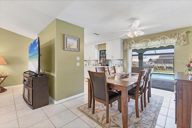 dining space with light tile patterned floors, a textured ceiling, a ceiling fan, and baseboards