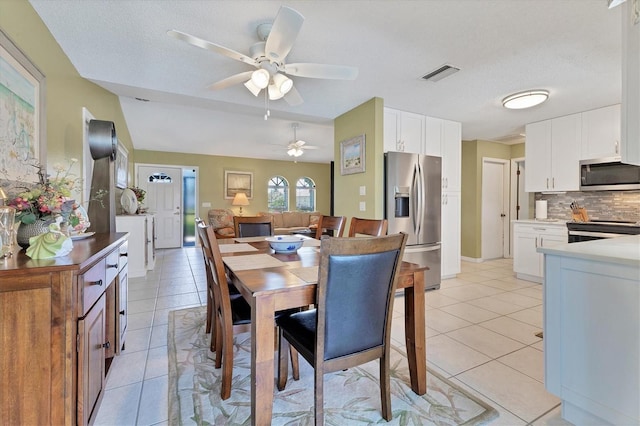 dining space with a ceiling fan, light tile patterned floors, and a textured ceiling