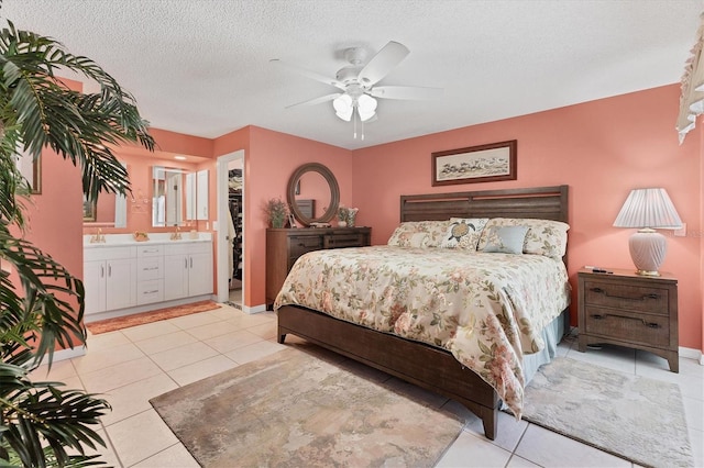 bedroom featuring light tile patterned floors, a textured ceiling, connected bathroom, ceiling fan, and a sink