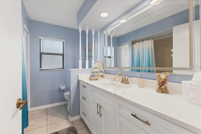 bathroom with toilet, tile patterned flooring, baseboards, and healthy amount of natural light