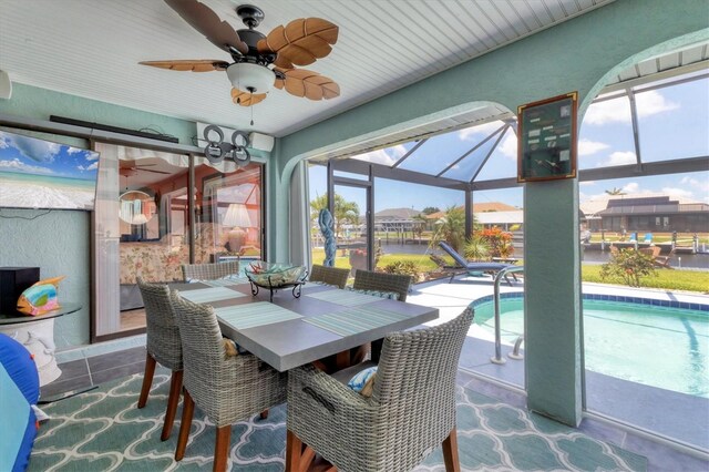 sunroom featuring a ceiling fan, plenty of natural light, and outdoor dining space