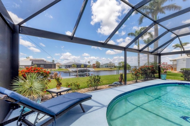 outdoor pool with a water view, glass enclosure, a lawn, and a patio