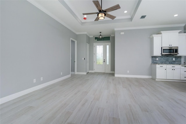 13344 Gershwin Ln, Port Charlotte, FL 33981 - unfurnished living room with a tray ceiling, ceiling fan, light wood finished floors, crown molding, and recessed lighting