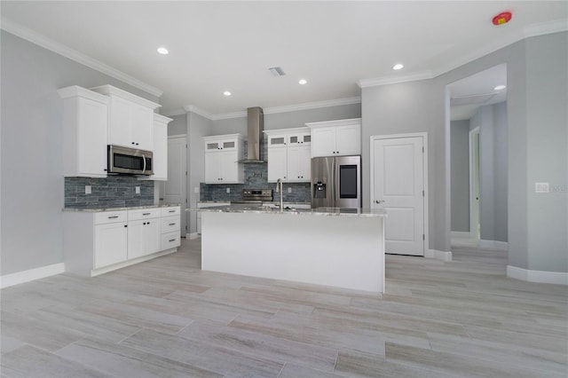 13344 Gershwin Ln, Port Charlotte, FL 33981 - kitchen featuring appliances with stainless steel finishes, wall chimney exhaust hood, a kitchen island with sink, decorative backsplash, and white cabinetry