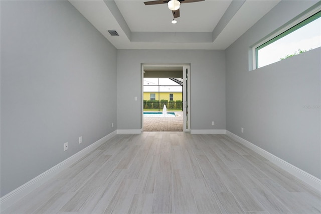 13344 Gershwin Ln, Port Charlotte, FL 33981 - empty room featuring a tray ceiling, a ceiling fan, light wood-type flooring, and baseboards