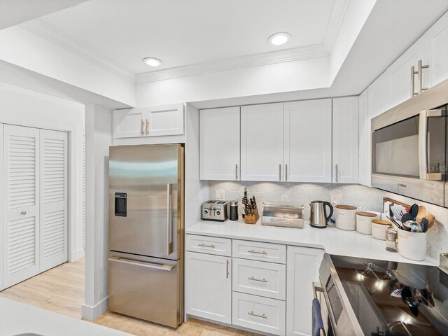 420 Gulf Blvd Unit 4, Boca Grande, FL 33921 - kitchen with stainless steel appliances, backsplash, crown molding, light countertops, and light wood finished floors