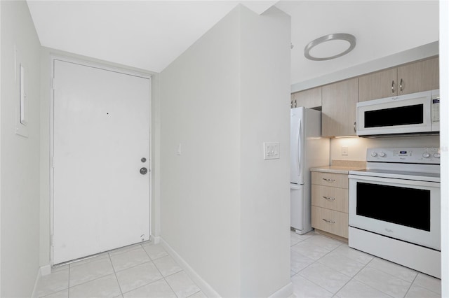 1551 Beach Rd Unit 212, Englewood, FL 34223 - kitchen featuring white appliances, light brown cabinetry, light tile patterned floors, and light countertops