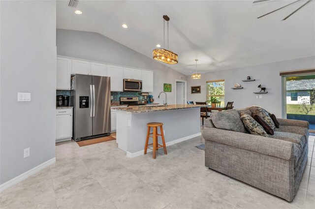 2678 Alva St, North Port, FL 34291 - kitchen featuring stainless steel appliances, vaulted ceiling, open floor plan, white cabinetry, and light stone counters