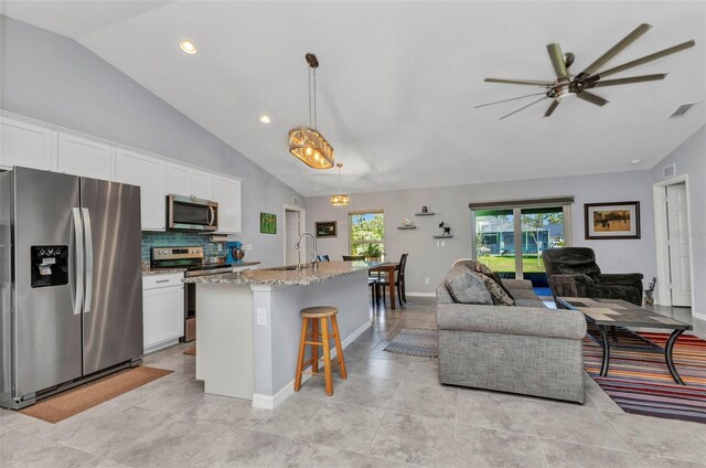 2678 Alva St, North Port, FL 34291 - kitchen featuring stainless steel appliances, open floor plan, light stone countertops, a breakfast bar area, and white cabinetry
