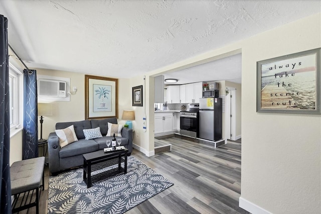 115 Friendship Ln, Englewood, FL 34223 - living room featuring a textured ceiling, an AC wall unit, wood finished floors, and baseboards