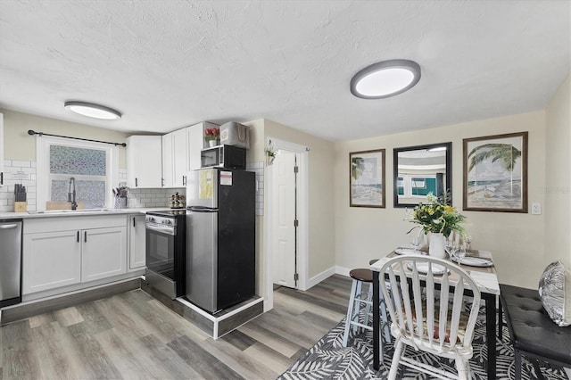 115 Friendship Ln, Englewood, FL 34223 - kitchen featuring stainless steel appliances, a sink, decorative backsplash, light countertops, and white cabinets