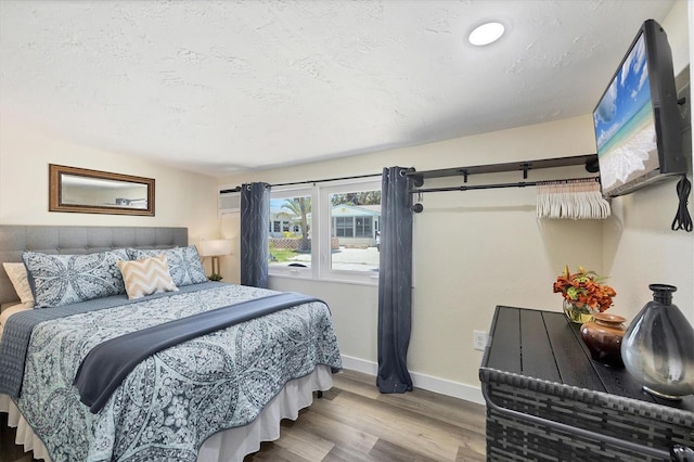 115 Friendship Ln, Englewood, FL 34223 - bedroom with wood finished floors, baseboards, a wall mounted air conditioner, and a textured ceiling