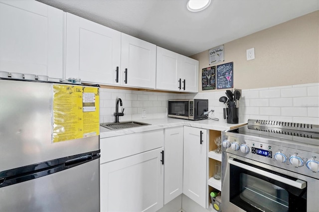 115 Friendship Ln, Englewood, FL 34223 - kitchen featuring appliances with stainless steel finishes, a sink, light countertops, white cabinetry, and backsplash