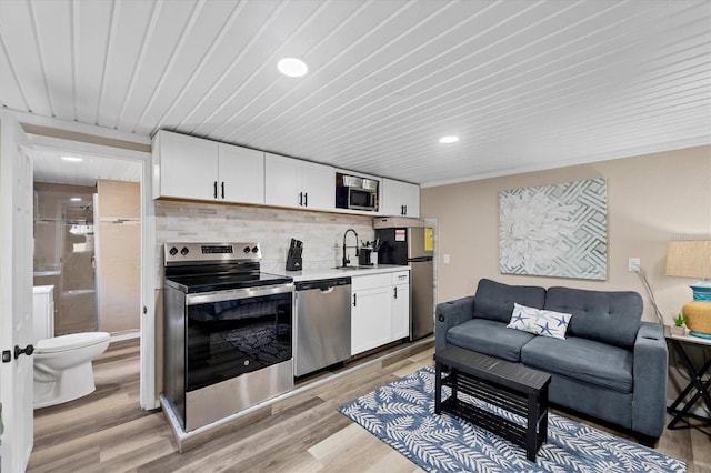 115 Friendship Ln, Englewood, FL 34223 - kitchen featuring appliances with stainless steel finishes, decorative backsplash, light wood-style floors, white cabinets, and recessed lighting