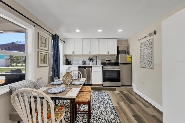 115 Friendship Ln, Englewood, FL 34223 - kitchen featuring appliances with stainless steel finishes, backsplash, white cabinets, wood finished floors, and recessed lighting