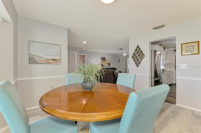 9869 Gulfstream Blvd, Englewood, FL 34224 - dining room featuring light wood-type flooring, a textured ceiling, and baseboards