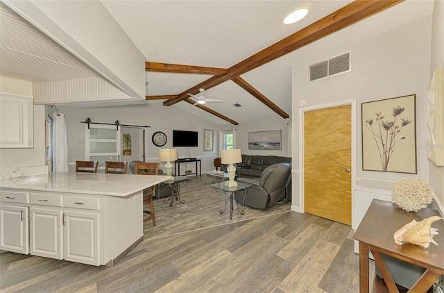9869 Gulfstream Blvd, Englewood, FL 34224 - kitchen featuring a barn door, a kitchen breakfast bar, white cabinets, and wood finished floors