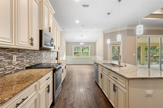 2758 Morrietta Ln, North Port, FL 34286 - kitchen with stainless steel appliances, cream cabinetry, a sink, dark wood-style flooring, and wainscoting