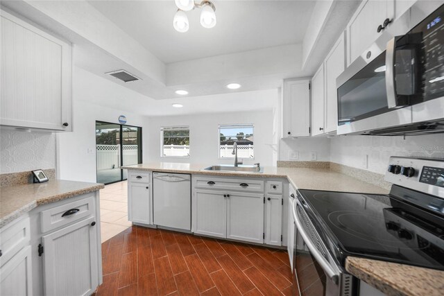 279 Mark Twain Ln, Rotonda West, FL 33947 - kitchen featuring stainless steel appliances, a sink, a tray ceiling, recessed lighting, and white cabinetry