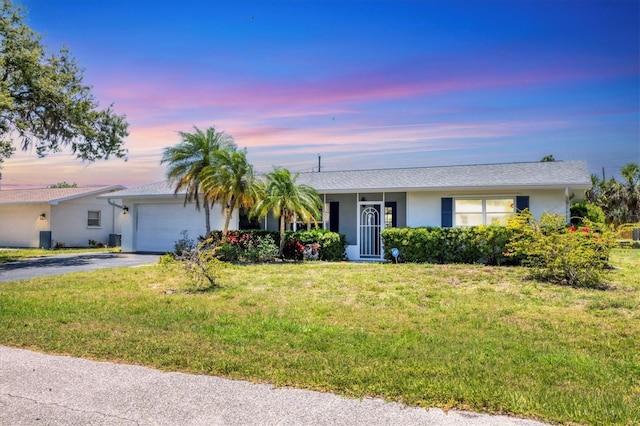 305 E Wentworth Cir, Englewood, FL 34223 - ranch-style house with a garage, driveway, a yard, and stucco siding