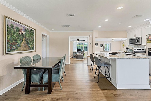 305 E Wentworth Cir, Englewood, FL 34223 - kitchen featuring stainless steel appliances, a ceiling fan, light wood-style floors, ornamental molding, and white cabinetry