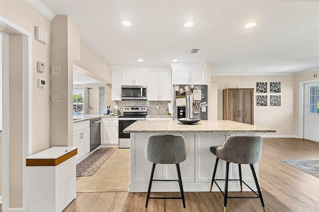305 E Wentworth Cir, Englewood, FL 34223 - kitchen featuring appliances with stainless steel finishes, a center island, a breakfast bar, white cabinetry, and tasteful backsplash