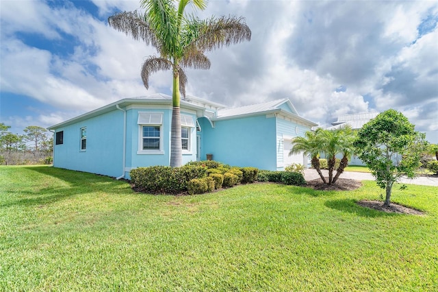 8952 Scallop Way, Placida, FL 33946 - view of home's exterior featuring stucco siding, a garage, a yard, and metal roof