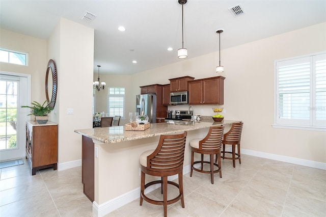 8952 Scallop Way, Placida, FL 33946 - kitchen featuring appliances with stainless steel finishes, a peninsula, a kitchen breakfast bar, light stone countertops, and recessed lighting