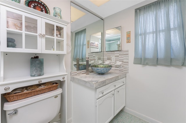 146 Rotonda Cir, Rotonda West, FL 33947 - bathroom featuring toilet, vanity, decorative backsplash, and baseboards