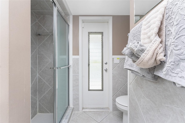 146 Rotonda Cir, Rotonda West, FL 33947 - bathroom featuring tile patterned floors, a stall shower, toilet, tile walls, and a wainscoted wall