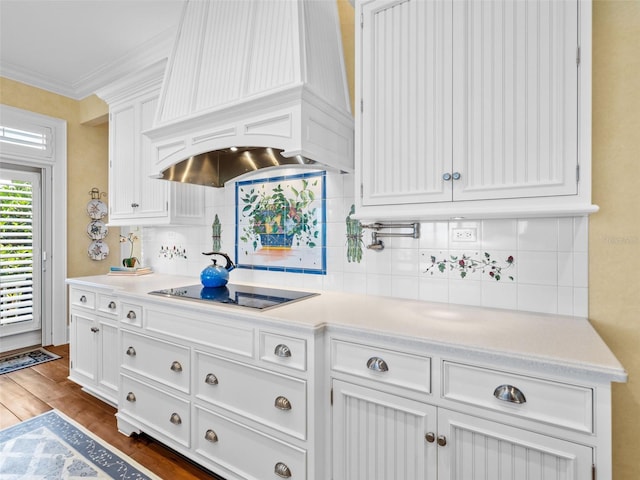 2979 Shore Ln, Boca Grande, FL 33921 - kitchen with custom exhaust hood, white cabinetry, black electric cooktop, light countertops, and crown molding
