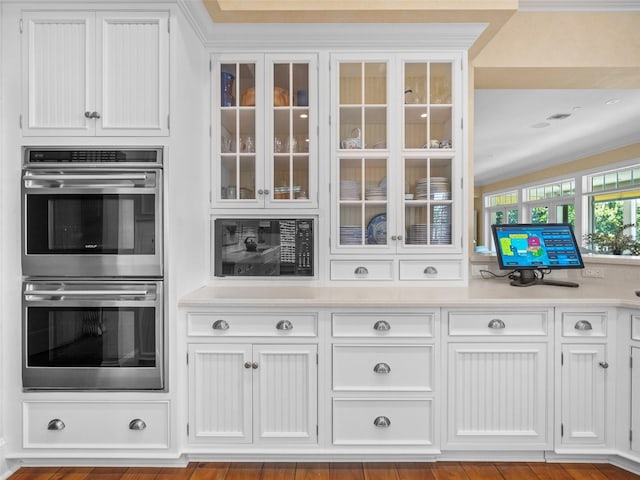 2979 Shore Ln, Boca Grande, FL 33921 - kitchen featuring double oven, white cabinets, glass insert cabinets, and light countertops