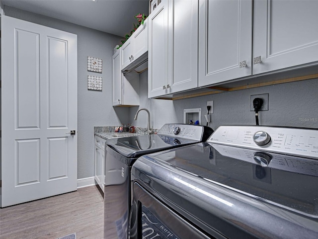 2590 Tarpon Cove Dr Unit 811, Punta Gorda, FL 33950 - laundry area featuring washer and clothes dryer, a textured wall, light wood finished floors, cabinet space, and baseboards