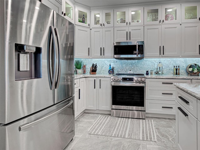 2590 Tarpon Cove Dr Unit 811, Punta Gorda, FL 33950 - kitchen featuring stainless steel appliances, white cabinetry, backsplash, light stone counters, and glass insert cabinets