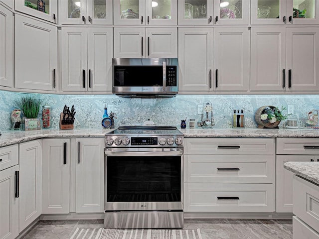 2590 Tarpon Cove Dr Unit 811, Punta Gorda, FL 33950 - kitchen with stainless steel appliances, light marble finish flooring, white cabinetry, and backsplash