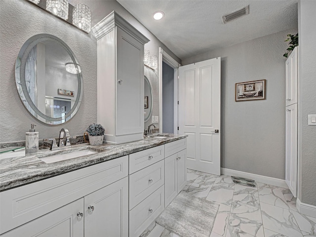 2590 Tarpon Cove Dr Unit 811, Punta Gorda, FL 33950 - bathroom with marble look tiles, double vanity, a textured wall, baseboards, and recessed lighting