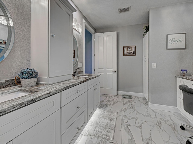 2590 Tarpon Cove Dr Unit 811, Punta Gorda, FL 33950 - bathroom featuring marble look tile flooring, double vanity, baseboards, and a textured wall