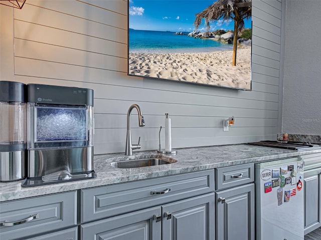 2590 Tarpon Cove Dr Unit 811, Punta Gorda, FL 33950 - kitchen featuring a sink, wooden walls, gray cabinets, light stone countertops, and stainless steel dishwasher
