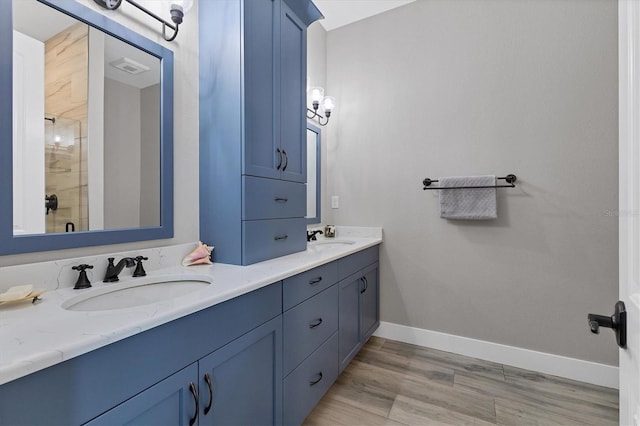 565 Green Dolphin Dr S, Placida, FL 33946 - bathroom with double vanity, a tile shower, wood finished floors, and baseboards