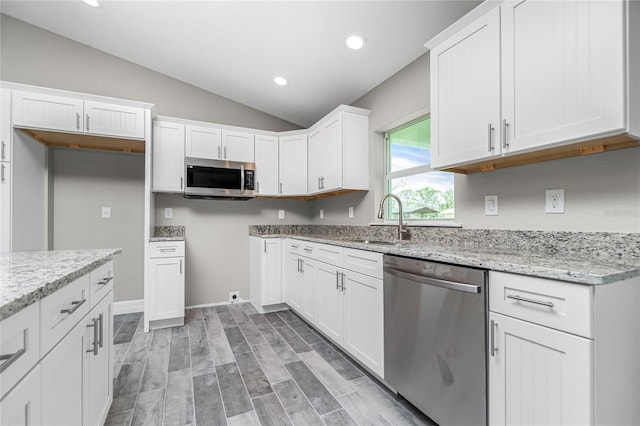 8270 Cook Ct, Port Charlotte, FL 33981 - kitchen with appliances with stainless steel finishes, a sink, light stone counters, white cabinets, and vaulted ceiling